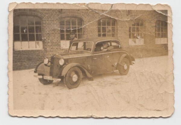 Samochód  na tle warsztatu w Rogoźnie, w aucie Franciszek Paszyk, fot. z archiwum prywatnego